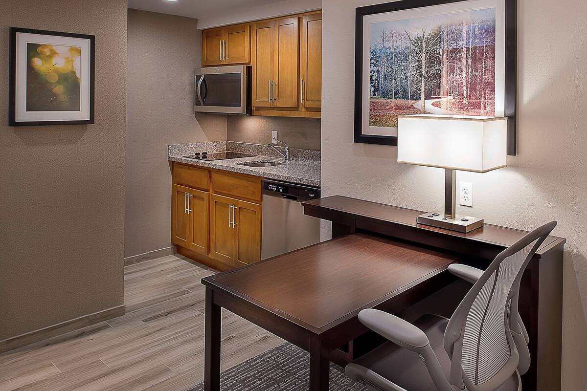 A compact kitchen with wooden cabinets, a built-in microwave, and a dishwasher.