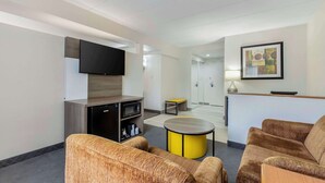A modern hotel lobby with a flat-screen TV, a reception desk, a round yellow table, and two brown sofas. - Comfort Inn Herndon - Reston (Herndon)