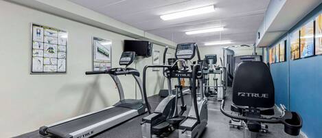 Un gimnasio con cintas de correr, elípticas y equipo de pesas.