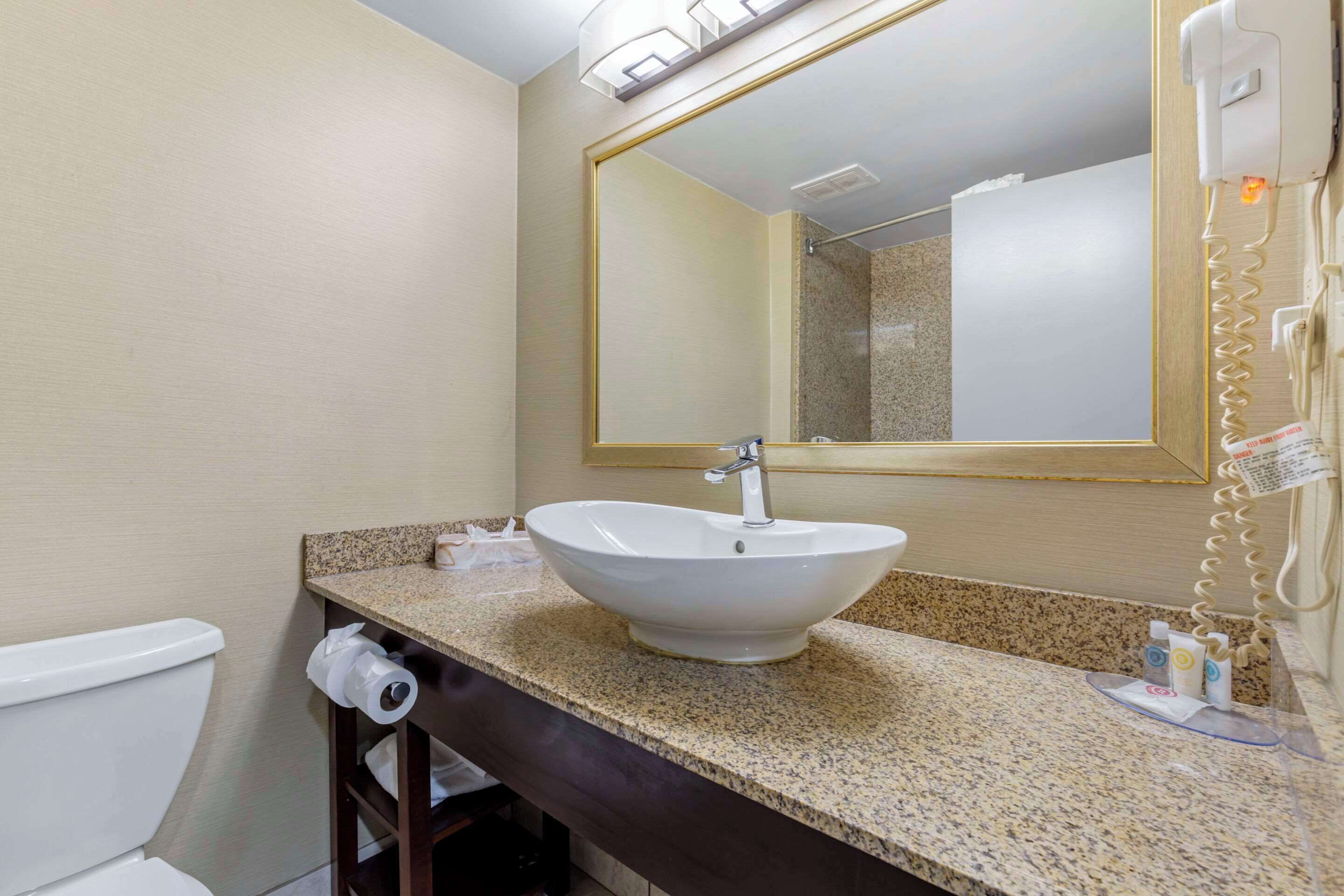 A bathroom with a sink, mirror, and telephone.