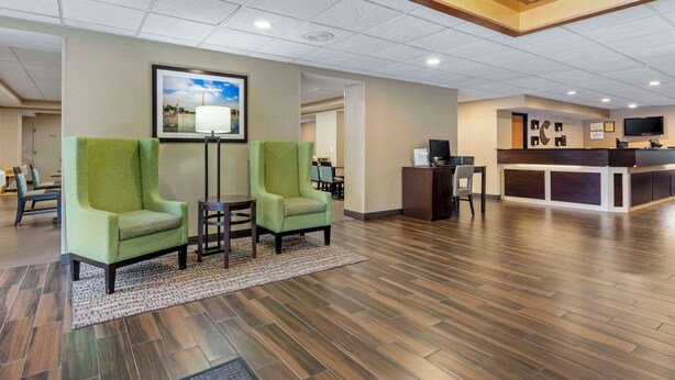 A hotel lobby with two green armchairs, a reception desk, and a television. - Comfort Inn Herndon - Reston (Herndon)