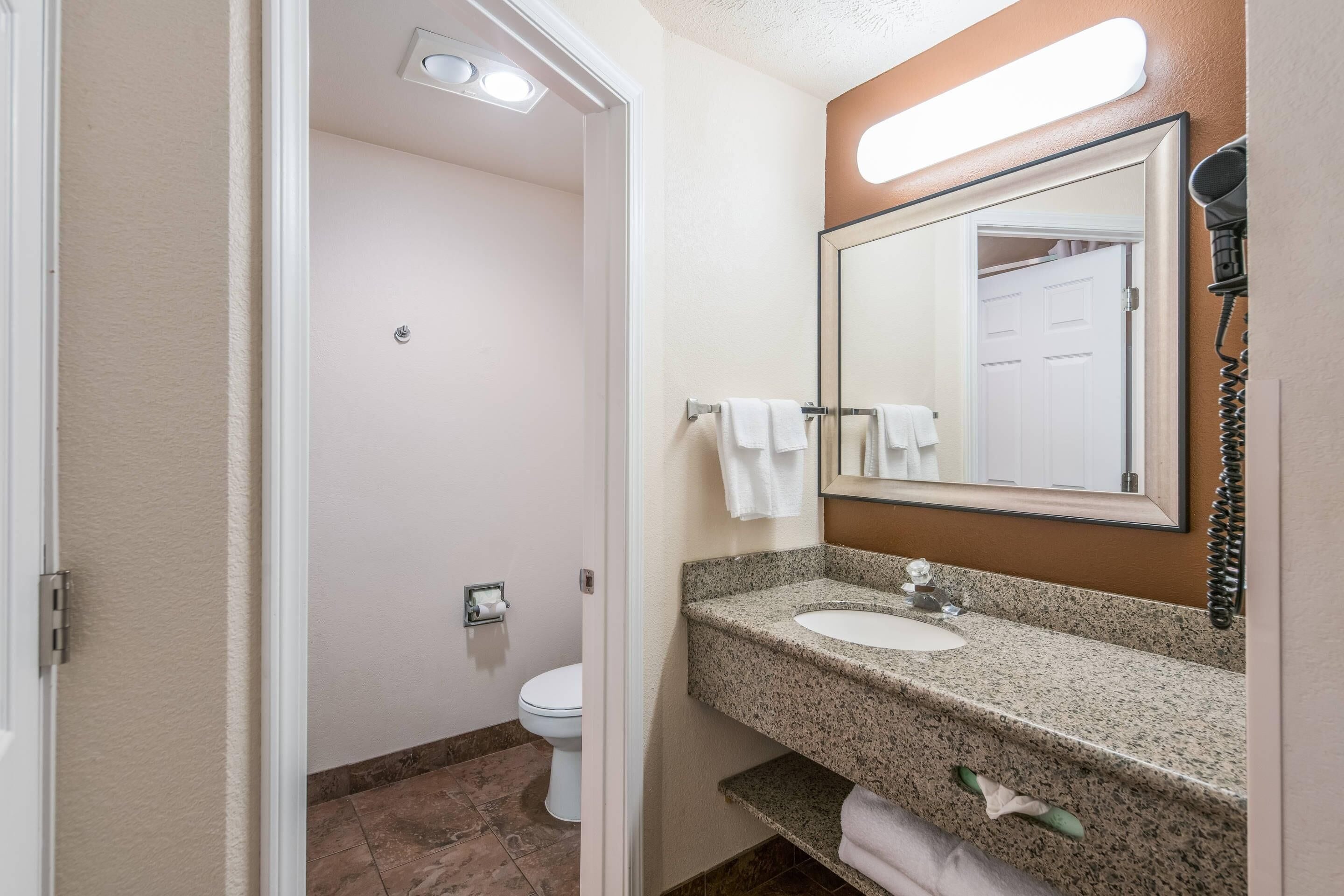Een badkamer met toilet, wastafel en spiegel.