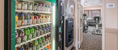 Máquina expendedora llena de diversas bebidas y un refrigerador.