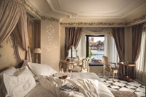 A hotel room with a bed, a desk, a chair, a round table, and a view of a body of water.