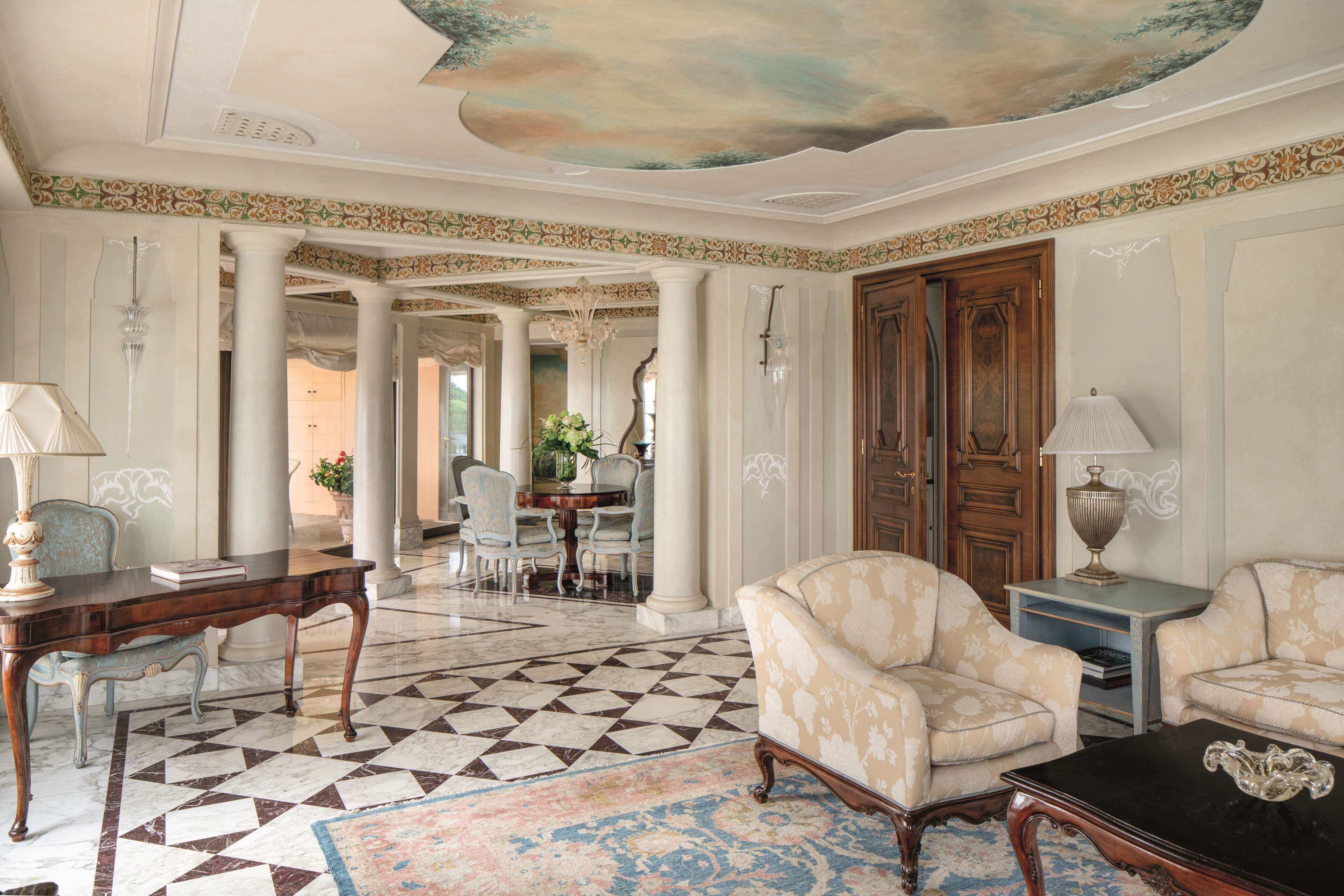 A spacious room with a checkered floor, a round table, and two armchairs.