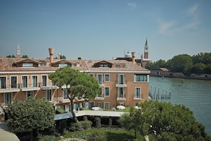 A large, multi-story hotel with a terracotta roof, located near a body of water.