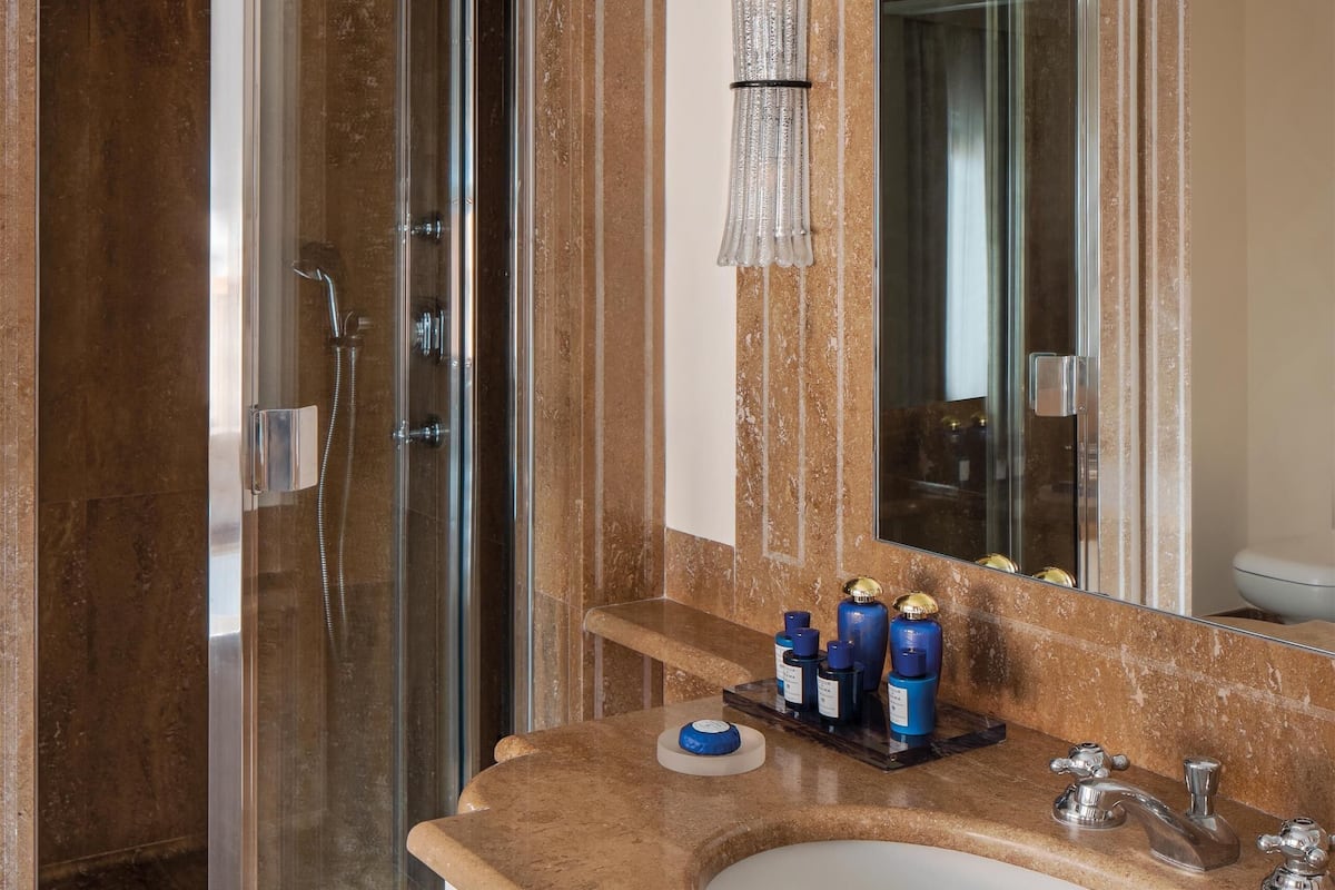 A bathroom with a glass-enclosed shower, a marble sink, and a large mirror.