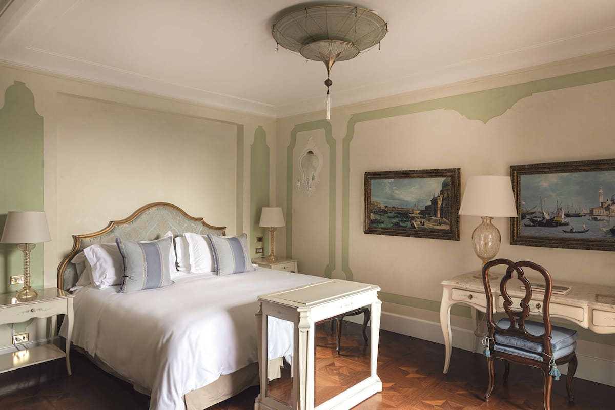 A neatly arranged bedroom with a bed, bedside tables, a desk, and a chair.