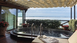 Un bain à remous avec vue sur la mer, entouré de plantes en pot et doté d’un espace abrité.