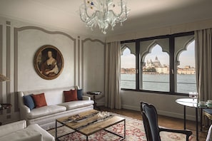 A room with a white sofa, a coffee table, and a view of a historic building across a body of water.