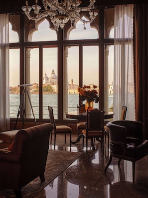 Ein Zimmer mit Blick auf Venedig, ausgestattet mit einem Chandelier, einem Stativ und einem Tisch mit Stühlen.