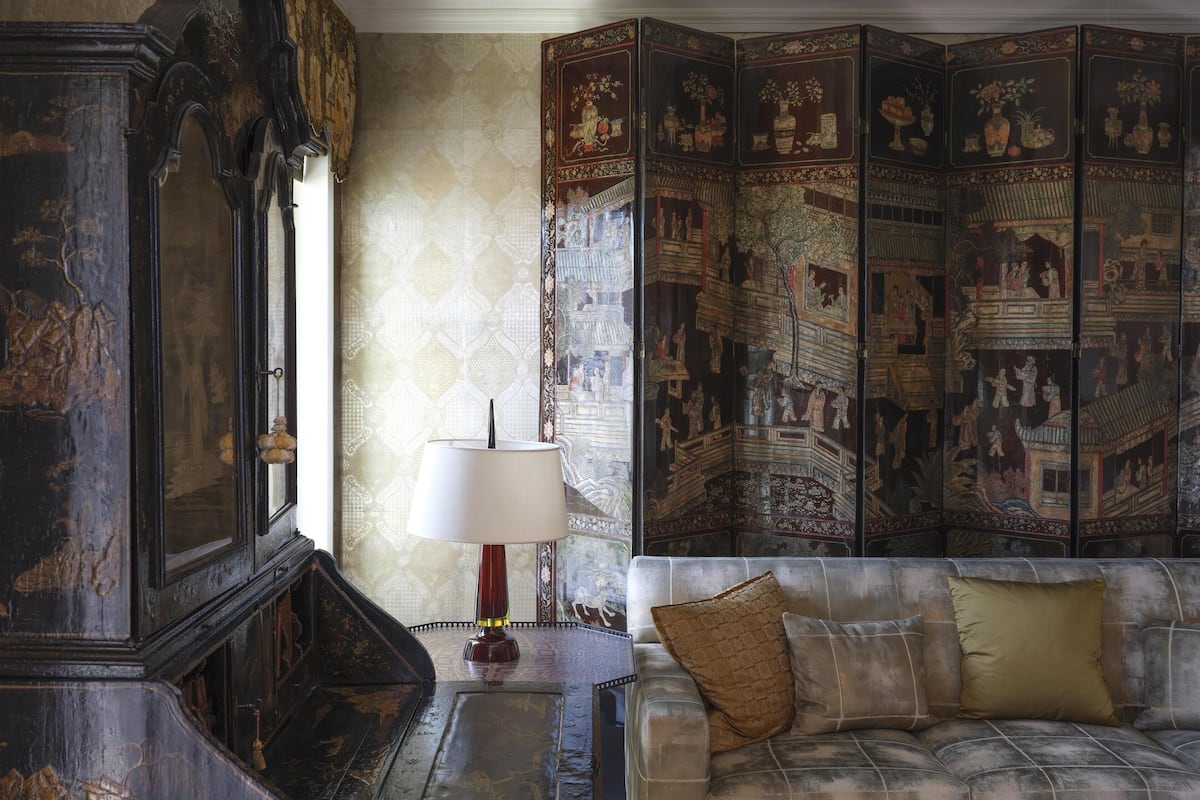 A traditional room with a sofa, a lamp, and a decorative screen with intricate designs.