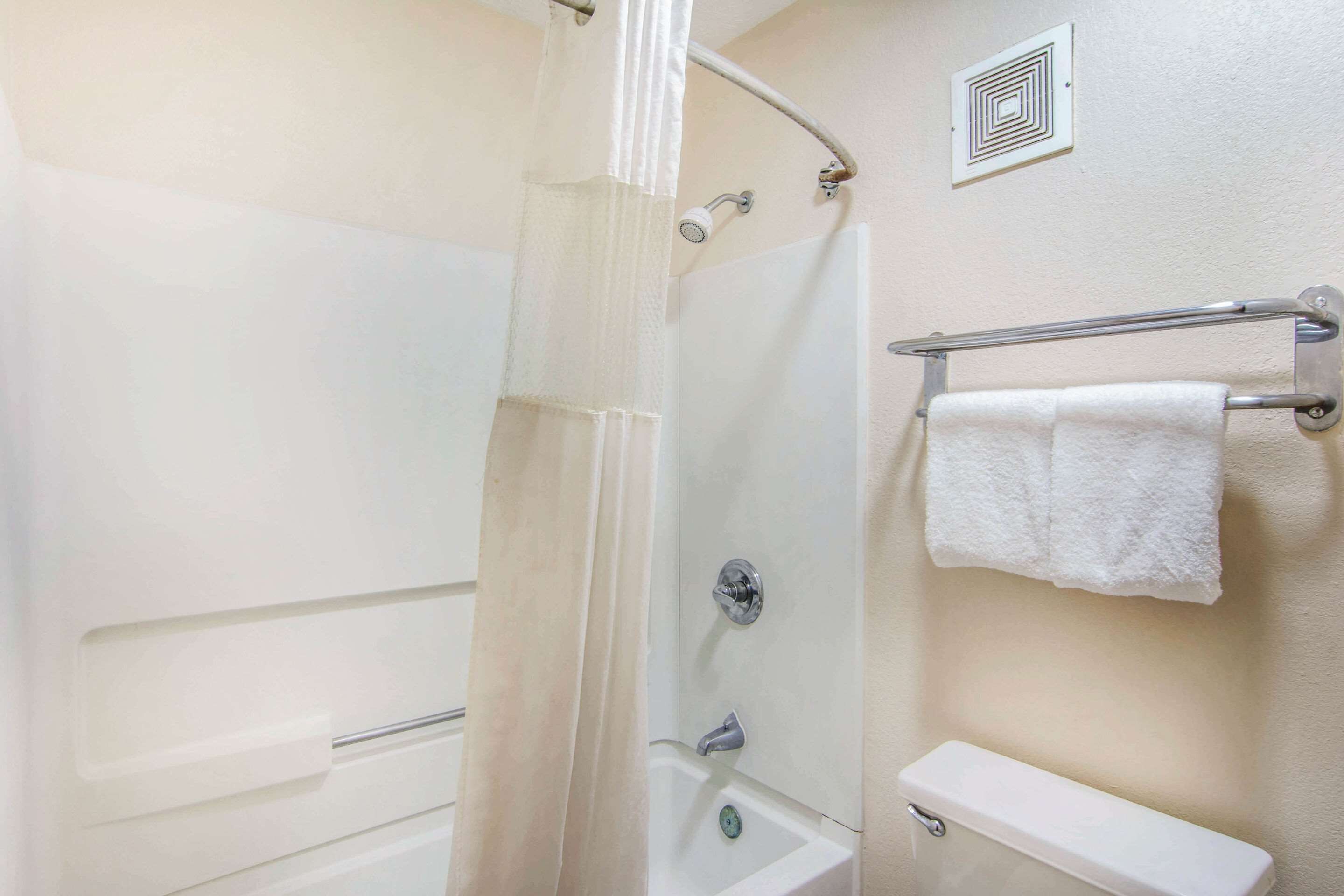 A bathroom with a shower, a toilet, and a towel rack.