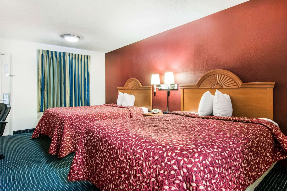 A hotel room with two beds, a desk, and a chair.