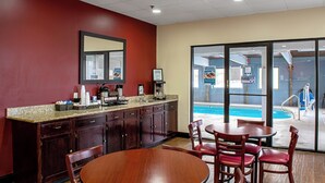Ein Restaurant mit Blick auf einen Pool, eine Theke mit Kaffeemaschinen und ein Essbereich mit Stühlen.