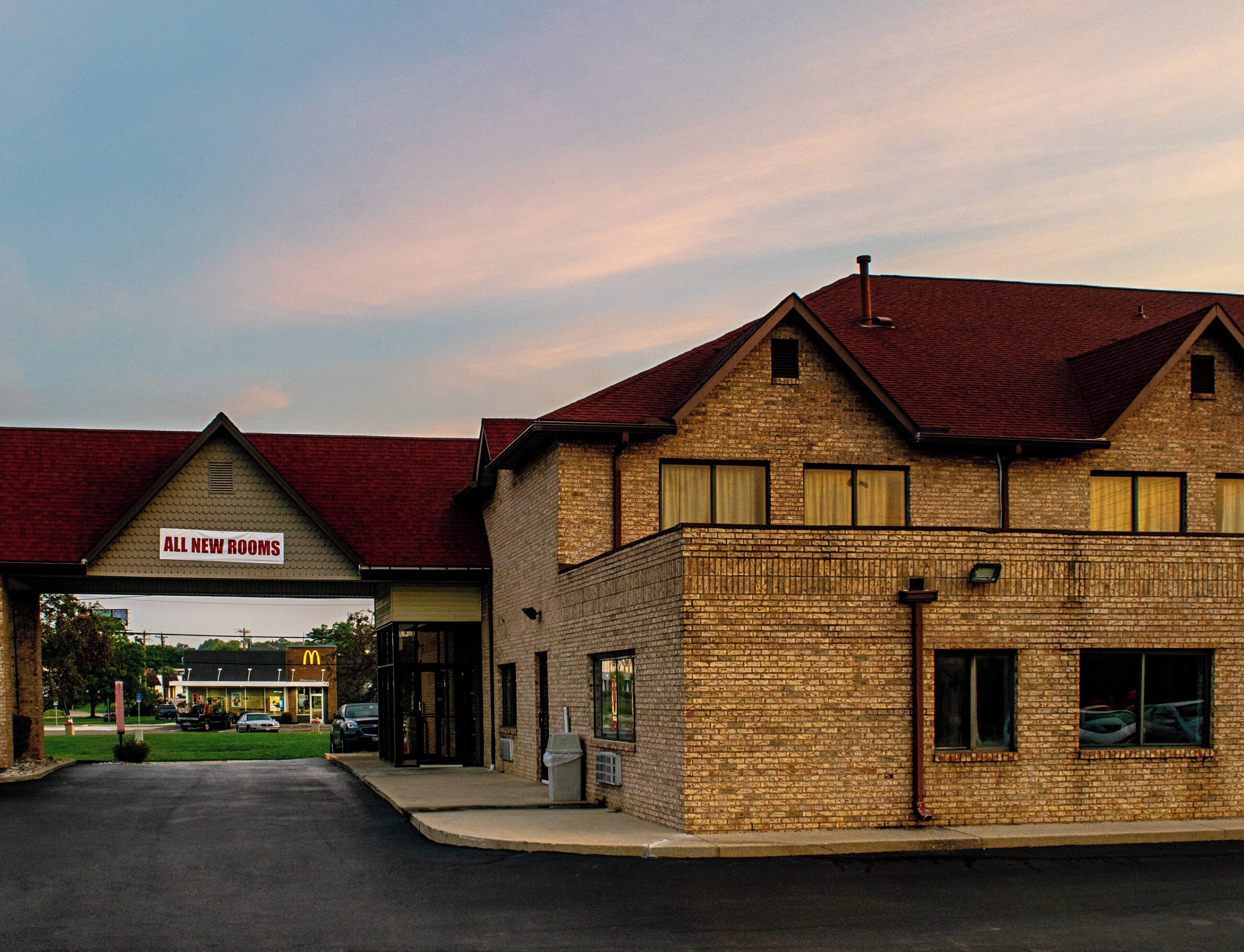 A building with a sign indicating 'ALL NEW ROOMS' and a McDonald's restaurant in the background.