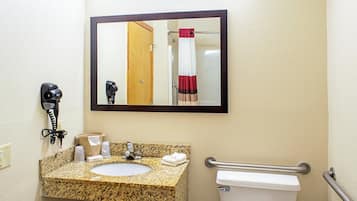 Un baño con lavamanos de granito, un espejo, un teléfono y un inodoro.