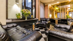 A modern lobby with leather sofas, a glass coffee table, and a large window with a view of the city. - Hotel Brunelleschi (Milan)