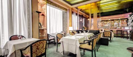 A restaurant with tables set for dining, a bar area, and a patterned floor.