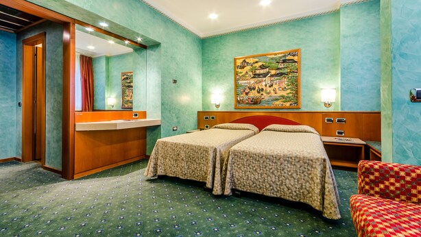 Une chambre d’hôtel avec deux lits, une salle de bain avec un lavabo et un grand tableau au mur.