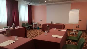 Una sala conferenze con tavoli, sedie, uno schermo per proiezioni e una moquette decorata.