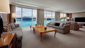 Amplia sala de estar con un gran ventanal que ofrece vistas al mar y a las montañas. Hay dos sofás, una mesa de centro y un televisor.