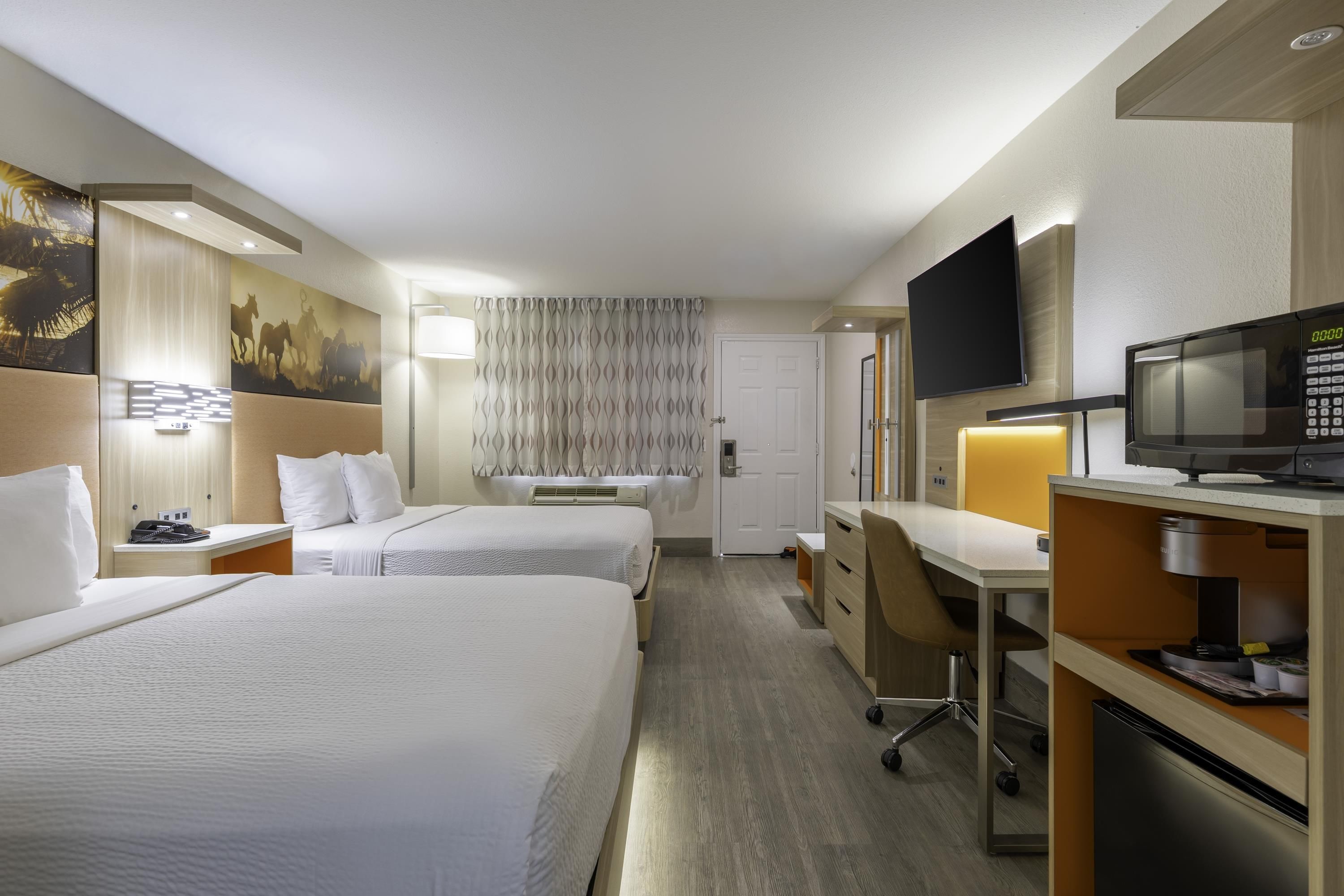Habitación de hotel con dos camas, un escritorio, un televisor y un minibar.