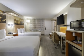 A hotel room with two beds, a desk, a television, and a minibar. - Days Inn by Wyndham Granbury (Granbury)