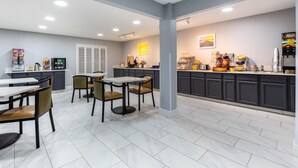 A modern kitchen area with a counter, seating, and various appliances. - Days Inn by Wyndham Granbury (Granbury)