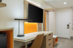 Habitación moderna con escritorio, silla y televisor montado.