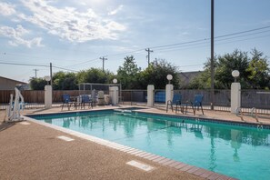 A swimming pool with a tiled edge, surrounded by a fence, and a clear sky above. - Days Inn by Wyndham Granbury (Granbury)