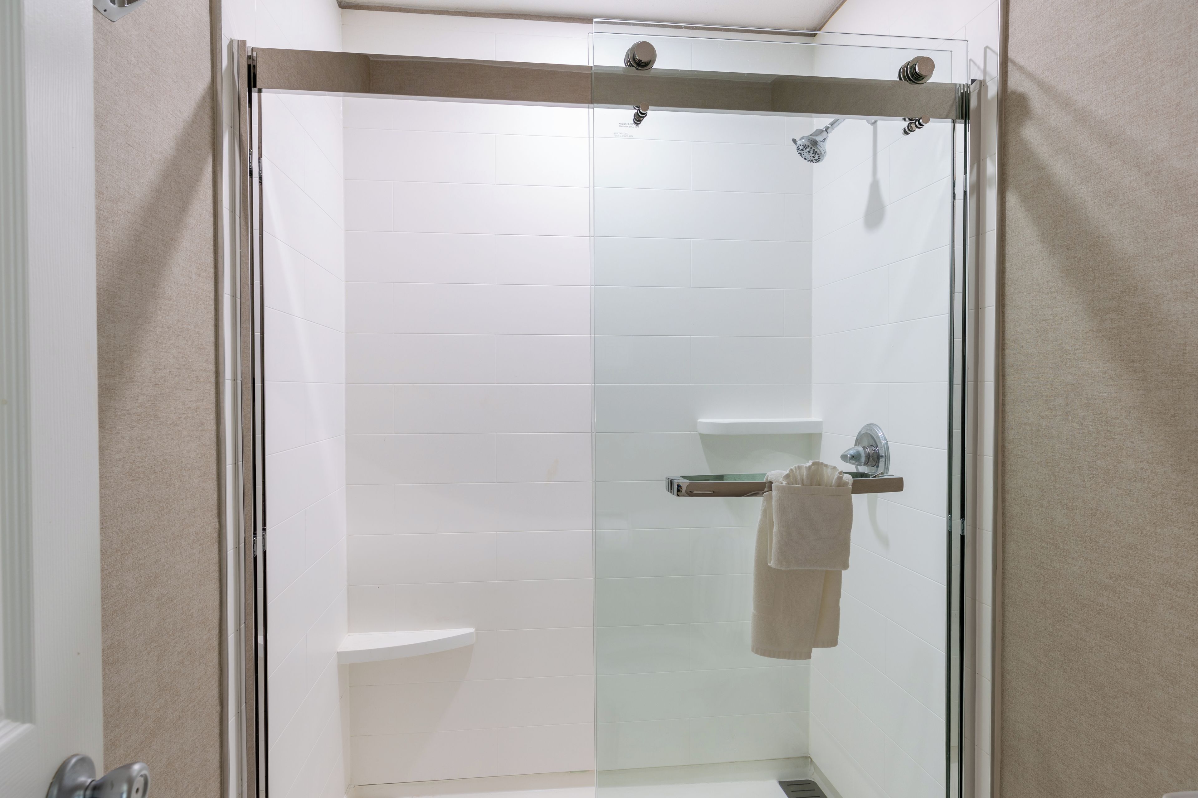 Cabina de ducha con paredes de vidrio, un inodoro y un perchero para toallas.