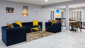 A modern living room with a dark blue sofa set, a glass coffee table, and a patterned rug. - Days Inn by Wyndham Granbury (Granbury)
