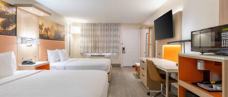 A hotel room with two beds, a desk, a television, and a microwave.