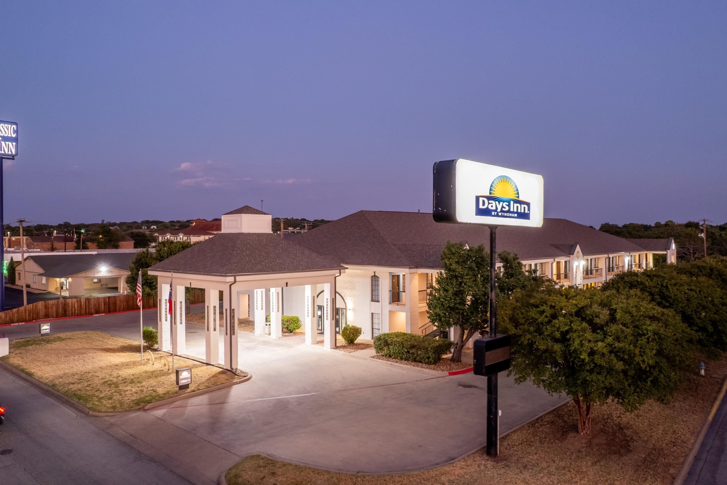 A hotel with a covered outdoor area, a parking lot, and a sign for Days Inn by Wyndham.