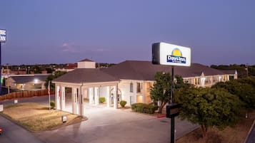 A hotel with a covered outdoor area, a parking lot, and a sign for Days Inn by Wyndham.