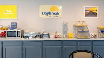 Un área de desayuno con un cartel que dice 'Daybreak Breakfast', un microondas, un tostador y una cafetera.