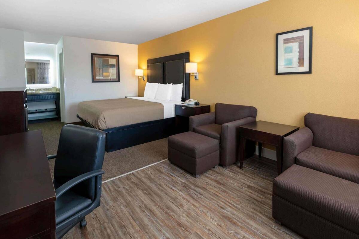 Ein Hotelzimmer mit Bett, Schreibtisch, Stuhl, Sofa und einem kleinen Tisch.