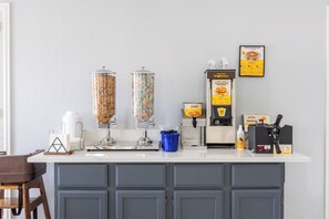 A kitchen counter with waffle dispensers, syrup, and waffle batter dispenser.