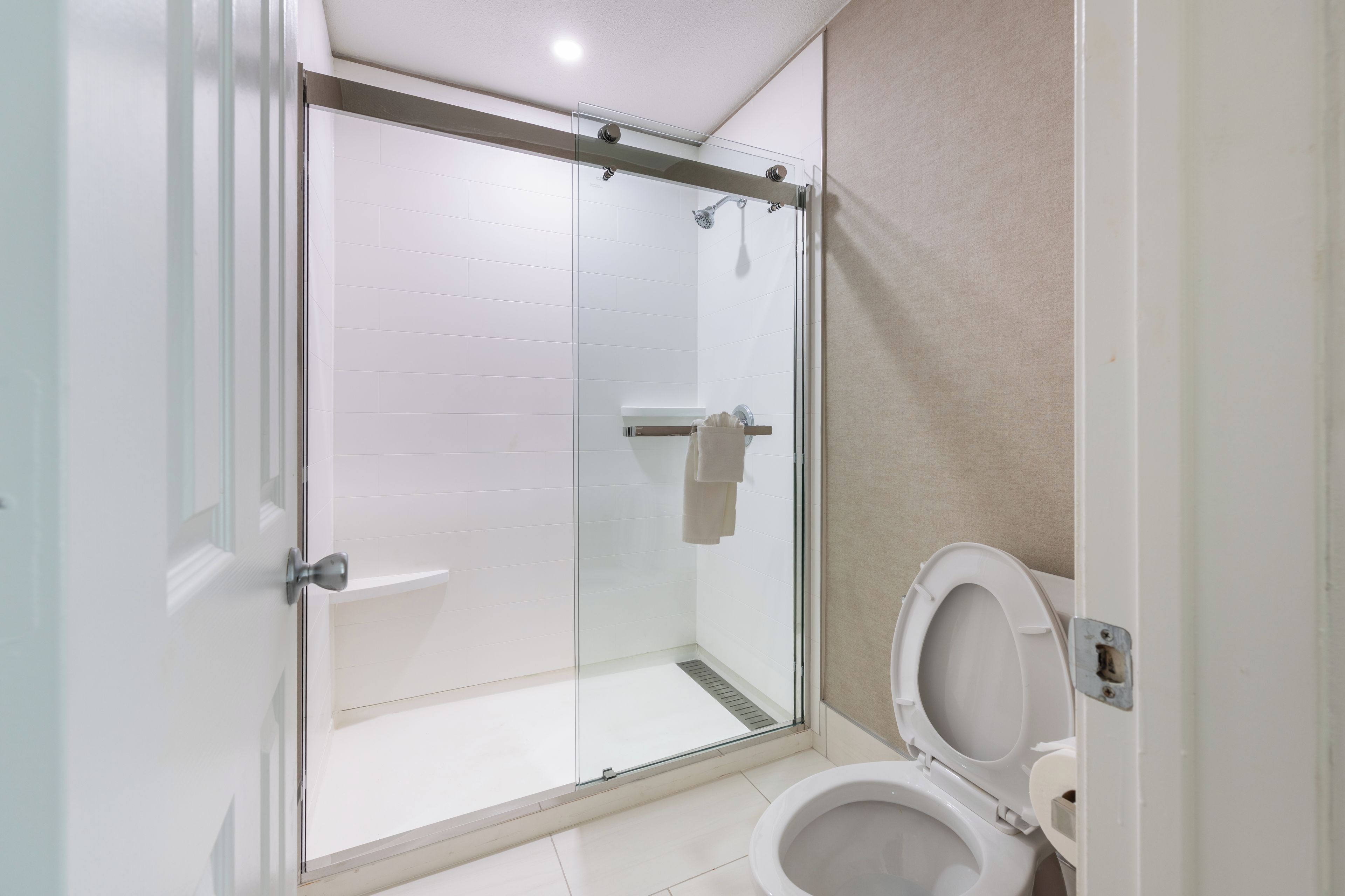 Ein modernes Badezimmer mit einer einteiligen Duschkabine, Toilette und Handtuchhalter.