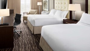 A hotel room with two beds, a desk, a chair, a TV, and a lamp. - Hilton Kansas City Airport (Kansas City)