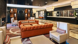 A modern lobby with leather sofas, a fireplace, and a reception desk. - Hilton Kansas City Airport (Kansas City)