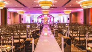A banquet hall with rows of chairs, a central aisle, and chandeliers. - Hilton Kansas City Airport (Kansas City)