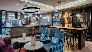 A modern bar area with seating, a counter, and a neon sign. - Premier Inn Köln City Centre (Cologne)