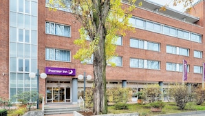 A brick building with a 'Premier Inn' sign, large windows, and a tree in the foreground. - Premier Inn Köln City Centre (Cologne)
