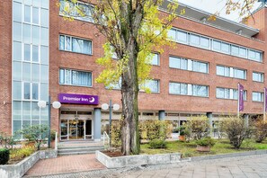Un edificio in mattoni con il cartello 'Premier Inn', ampie finestre e un albero sullo sfondo.