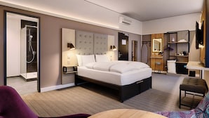 A modern hotel room with a large bed, a walk-in shower, a vanity with a mirror, and a television. - Premier Inn Köln City Centre (Cologne)