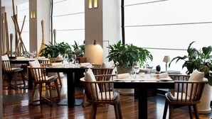 Un comedor con sillas y mesas de madera, plantas en macetas y una decoración de estilo moderno.
