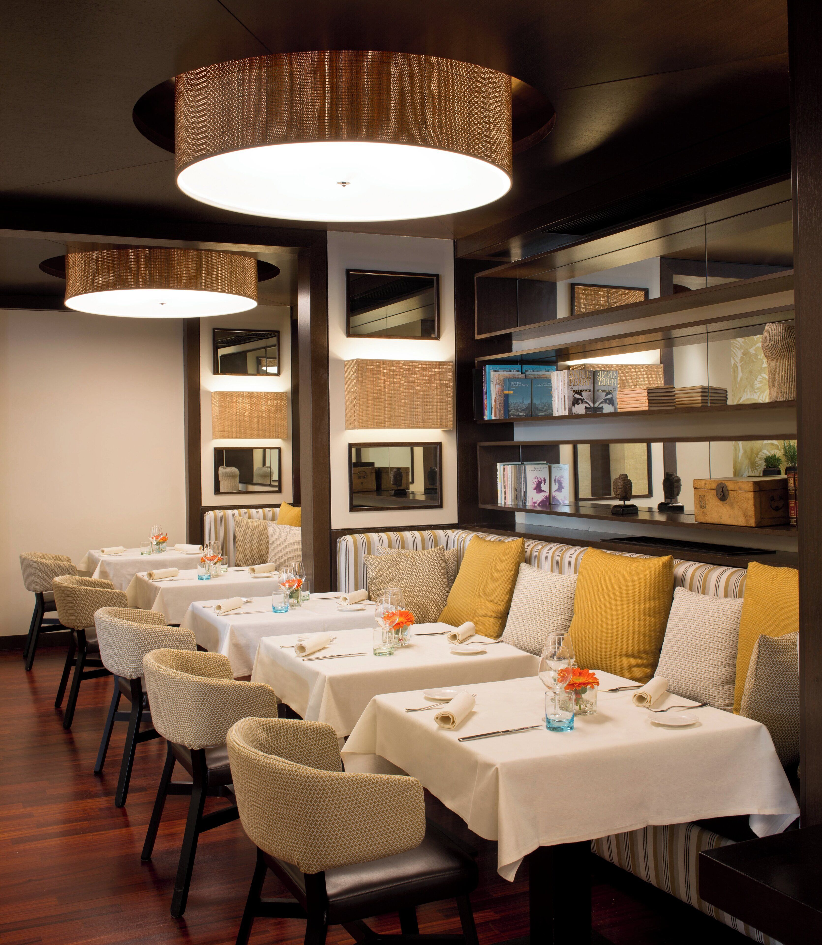 Un restaurant doté de nombreuses tables, chacune recouverte d’une nappe blanche et agrémentée de chaises et de compositions florales.