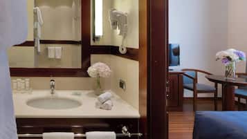 Un baño de hotel con lavamanos, toallero y secador de pelo montado en la pared.